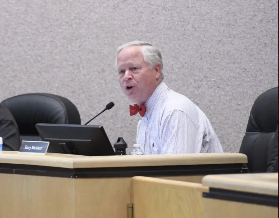 Terry McAteer speaking at a Nevada County public meeting, seated at the dais behind a nameplate reading Terry McAteer.